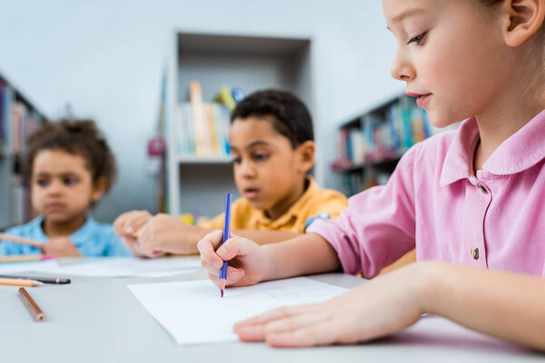 selective focus of cute kid drawing near african american children 