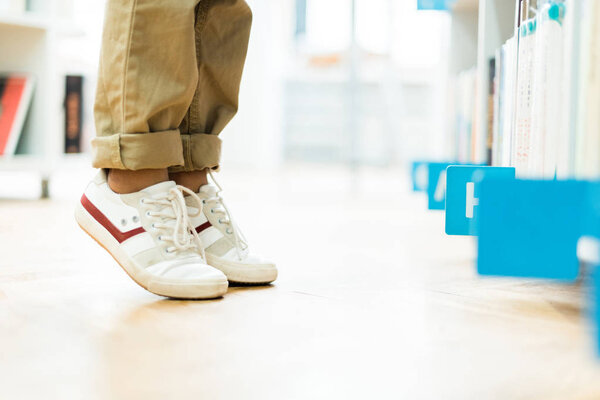 cropped view of kid standing on tip toe in white sneakers 