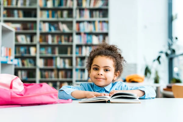 Lycklig Afrikansk Amerikansk Unge Sitter Och Tittar Kamera Nära Bok — Stockfoto