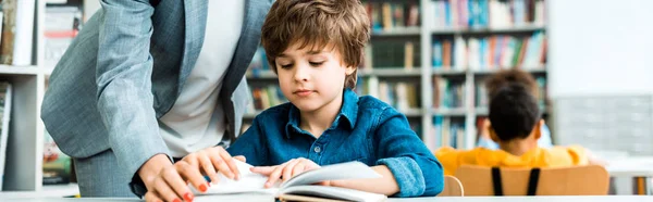 Panoramische Shot Van Vrouw Staande Buurt Van Schattig Kid Lezen — Stockfoto