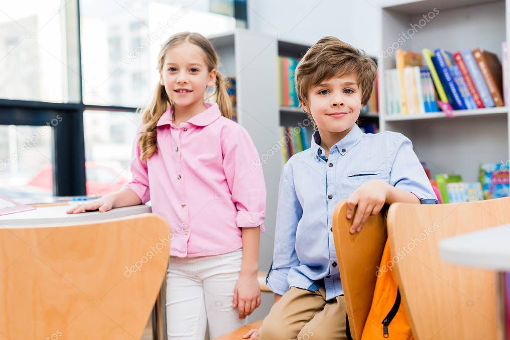 selective focus of cheerful kids looking at camera in library 