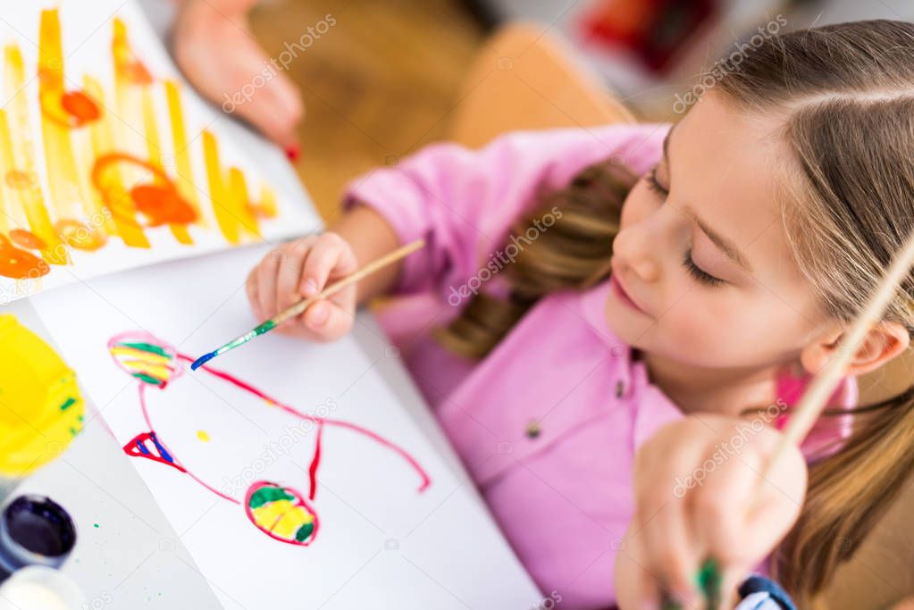 selective focus of cute kid painting on paper with paintbrush 