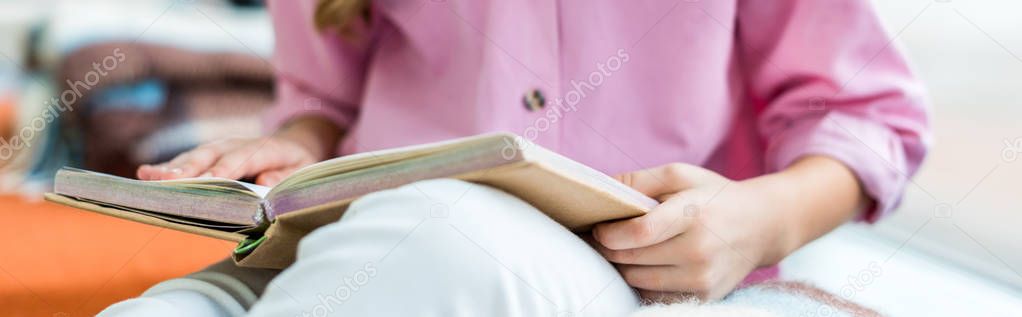 panoramic shot of kid sitting and holding book in hands 