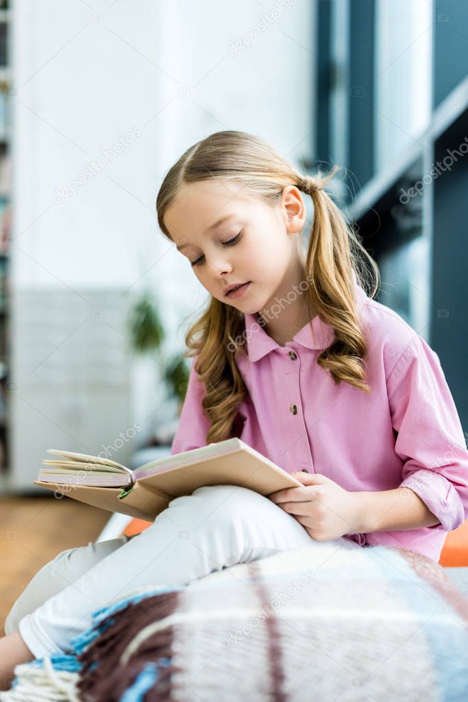 selective focus of cute kid sitting and reading book 