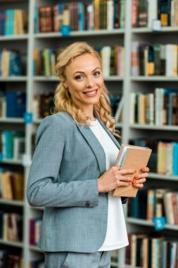 neşeli sarışın kadın kameraya bakarak ve kitap tutarak 