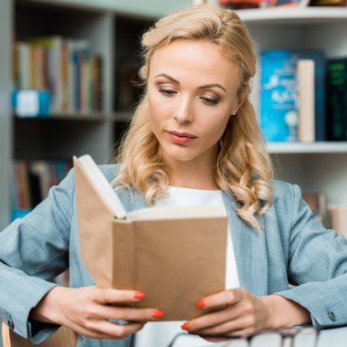 selective focus attractive blonde woman reading book  clipart