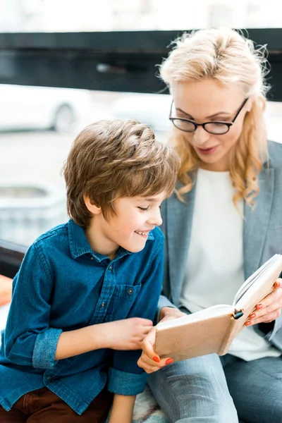 Enfoque Selectivo Niño Lindo Libro Lectura Cerca Mujer Atractiva —  Fotos de Stock