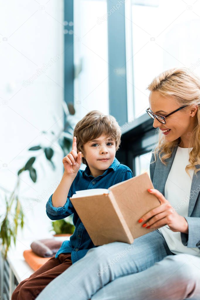 selective focus of happy woman in glasses looking at cute kid having idea 