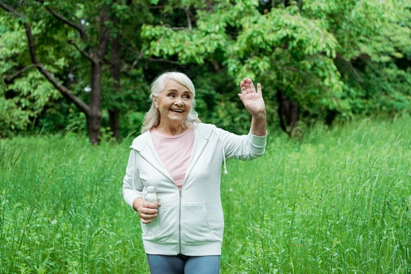 Cheerful Senior Woman Grey Hair Waving Hand Holding Bottle Water — Stock Photo, Image