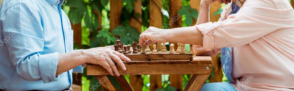 Панорамный снимок пары, играющей в шахматы на деревянном столе — стоковое изображение Панорамный Снимок Пары Играющей Шахматы Деревянном Столе — стоковое фото