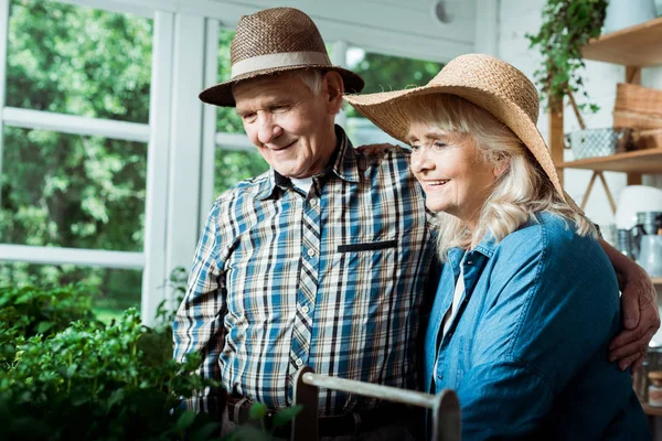 欢快的退休男人和女人微笑着 而看着绿色植物 — 图库照片