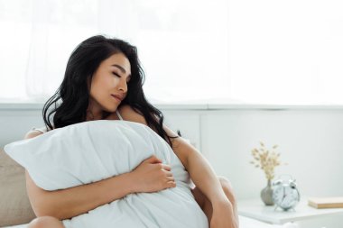  kapalı gözlü yatak odasında yastık tutan çekici asyalı kadın 