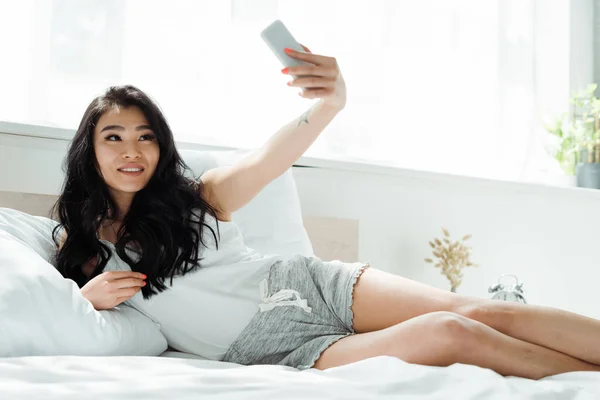 Selektywne Ostrości Wesoły Brunetka Asian Kobieta Biorąc Selfie Sypialni — Zdjęcie stockowe