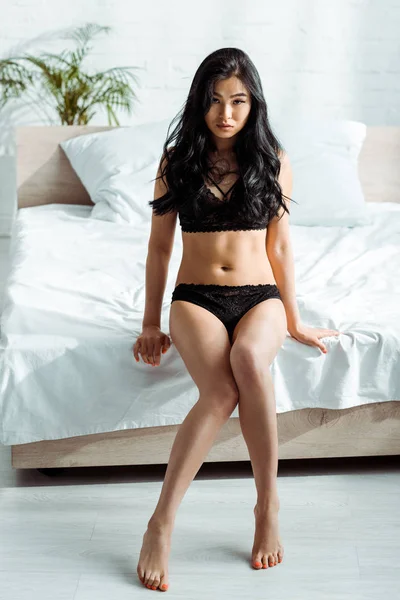自宅でベッドに座ってレースの黒いランジェリーでセクシーなタイの女性 — ストック写真