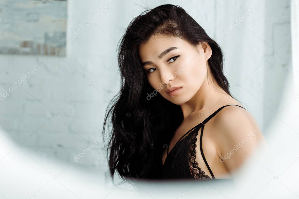 selective focus of sexy asian woman in lace underwear standing in bedroom 