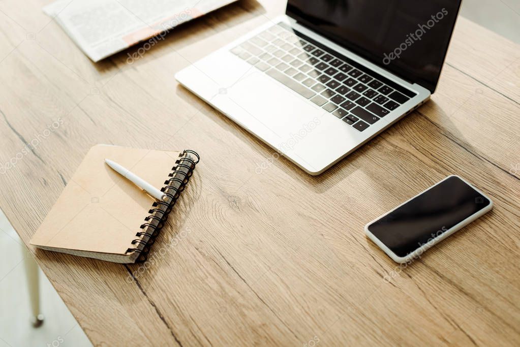 smartphone with blank screen near laptop and notebook with pen 