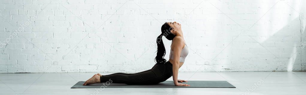 panoramic shot of beautiful brunette thai woman doing exercise on yoga mat 