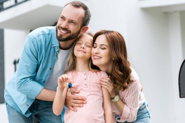 anahtar ile neşeli karısı ve çocuğu ile ayakta mutlu adam