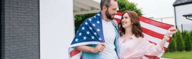 çekici kadın ile ayakta ve Amerikan bayrağı tutan mutlu sakallı adam panoramik çekim 