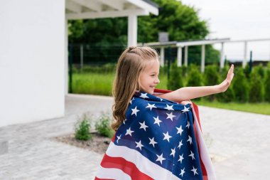 evin yakınında Amerikan bayrağı ile ayakta iken el sallayarak mutlu çocuk 