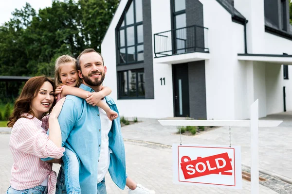 Happy Bearded Man Piggybacking Daughter Cheerful Wife Board Sold Letters — Stock Photo, Image