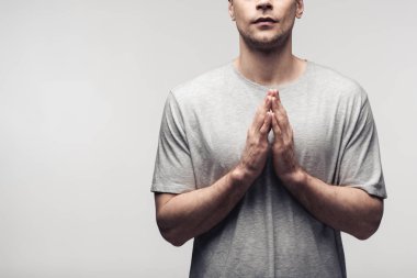 cropped view of man showing praying gesture isolated on grey, human emotion and expression concept clipart