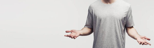 cropped view of man in grey t-shirt showing shrug gesture isolated on grey, panoramic shot, human emotion and expression concept