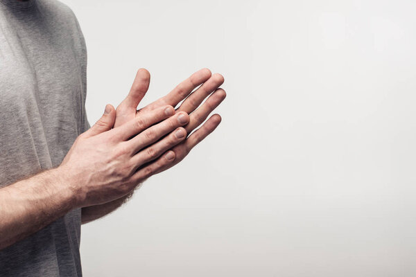 partial view of man rubbing hands isolated on grey, human emotion and expression concept