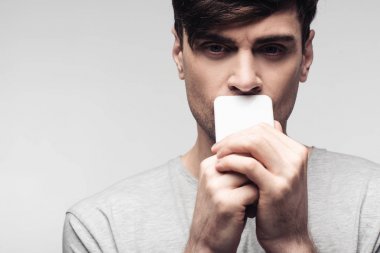 gri izole yüz yakın akıllı telefon tutan ciddi, düşünceli adam