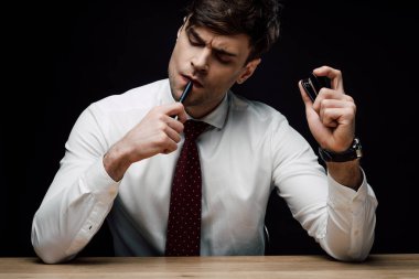 siyah izole zımba ve kalem tutan düşünceli işadamı