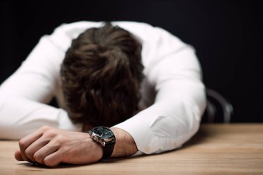 drunk, exhausted businessman lying on wooden table isolated on black  clipart