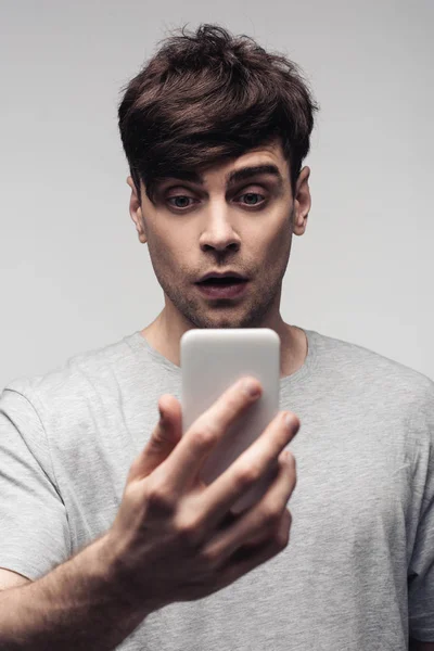 Έκπληκτος Νέος Άνθρωπος Κοιτάζοντας Smartphone Απομονωμένη Γκρι — Φωτογραφία Αρχείου