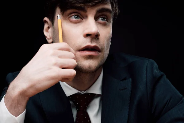 鉛筆で顔を触りながら目をそらす思慮深いビジネスマン — ストック写真