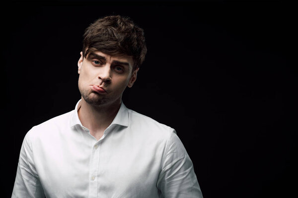 грустный, пьяный бизнесмен смотрит в камеру и гримасирует изолированный на черном
 