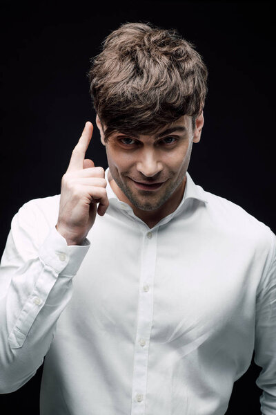 smiling businessman showing idea sign isolated on black, human emotion and expression concept