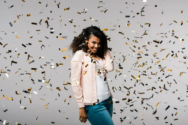 Feliz Menina Afro Americana Sorrindo Perto Confete Brilhante Enquanto Cinza — Fotografia de Stock