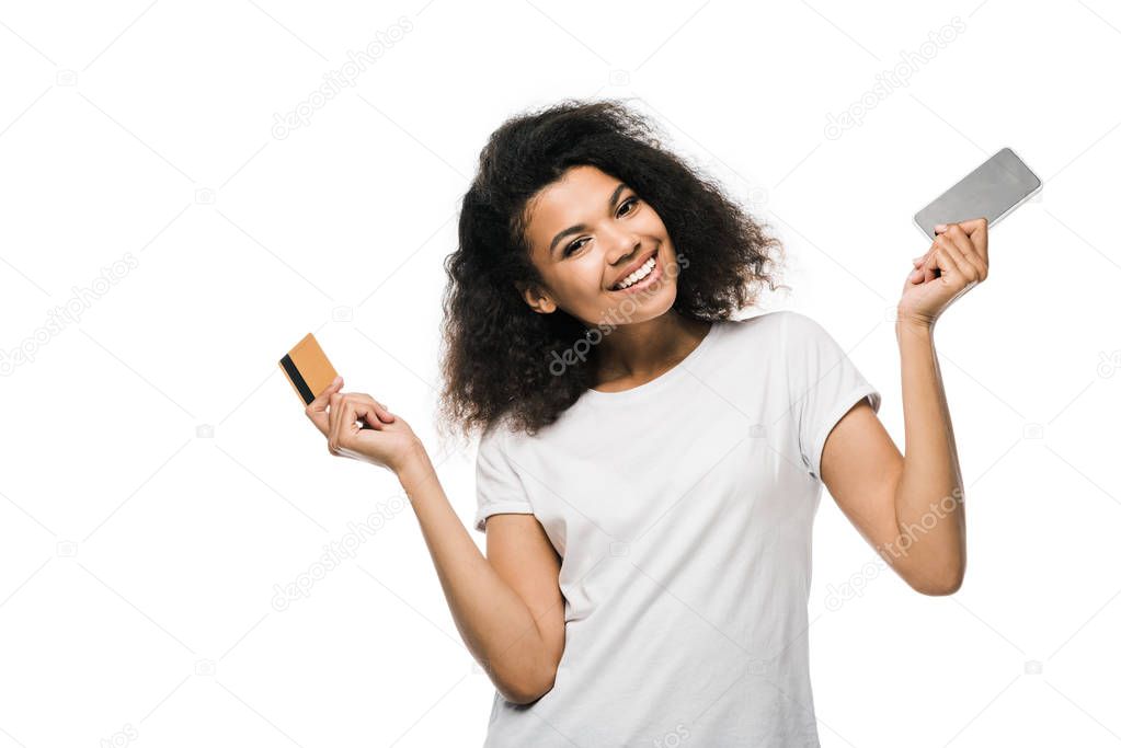 cheerful african american woman holding credit card and smartphone isolated on white 