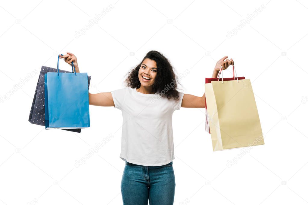 happy african american girl holding shopping bags while standing isolated on white 