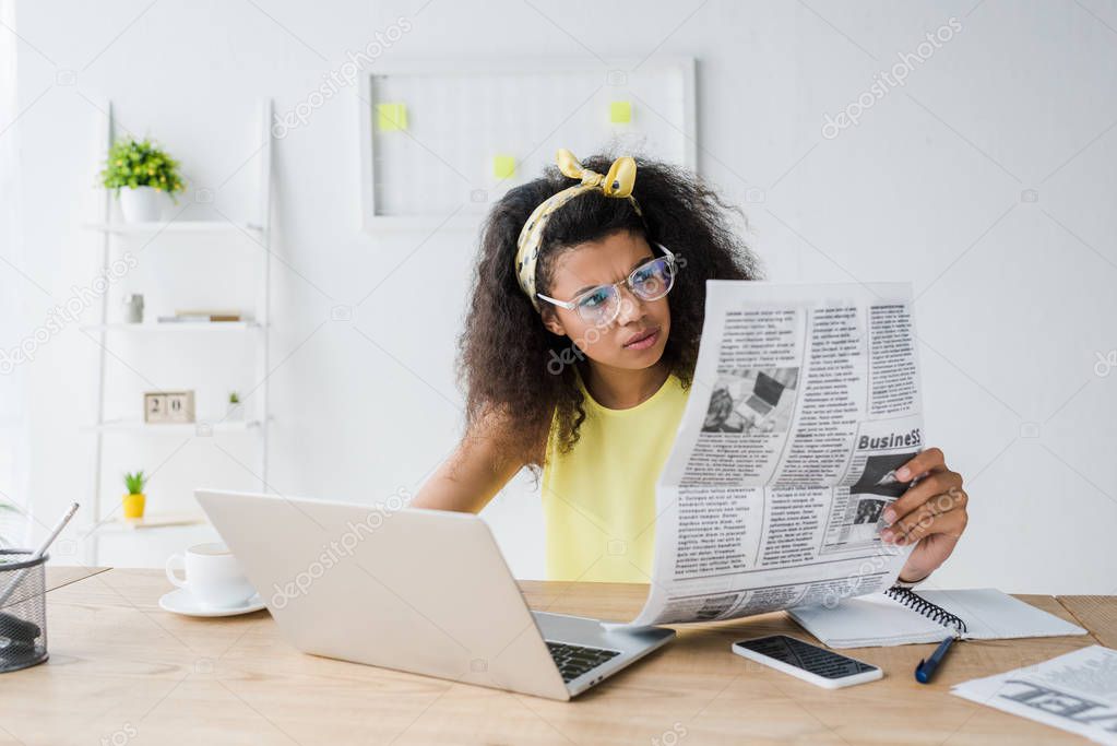 attractive african american woman reading travel newspaper near laptop 