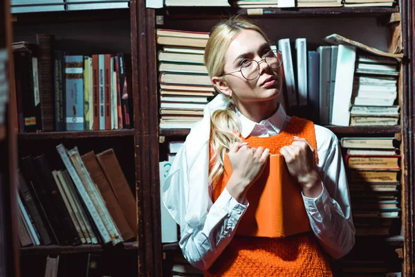 Блондинка Задумчивая Женщина Держит Книгу Смотрит Сторону Библиотеке — стоковое фото