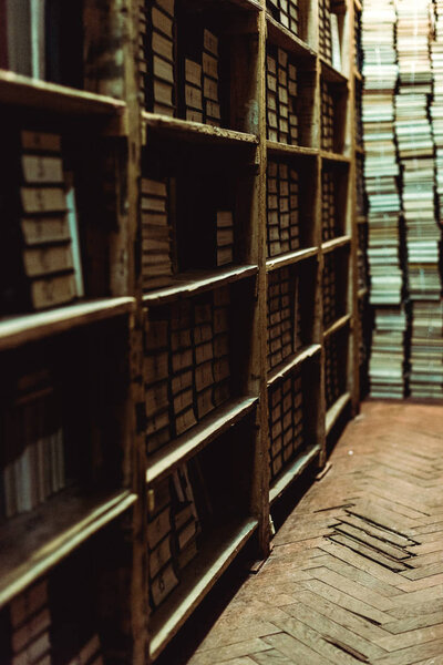 selective focus of retro books on wooden shelves in library 