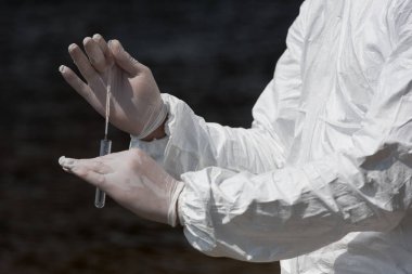partial view of water inspector in latex gloves with test tube taking water sample clipart