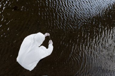 nehirden su örneği alarak koruyucu kostüm su denetçisi üst görünümü
