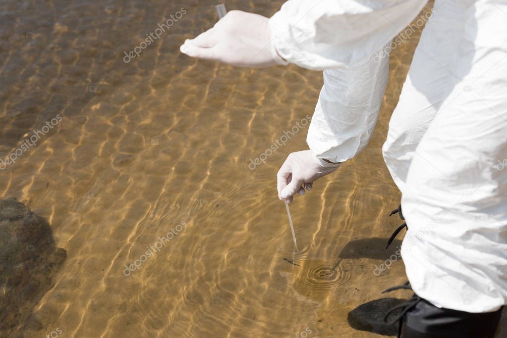 partial view of water inspector in latex gloves with test tube taking water sample