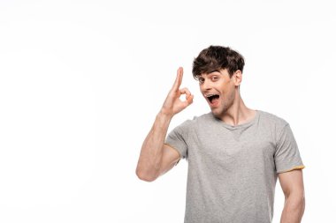 cheerful young man showing ok gesture while smiling at camera isolated on white clipart