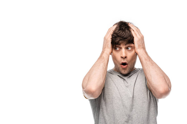 young discouraged man holding hands on head while looking away isolated on white