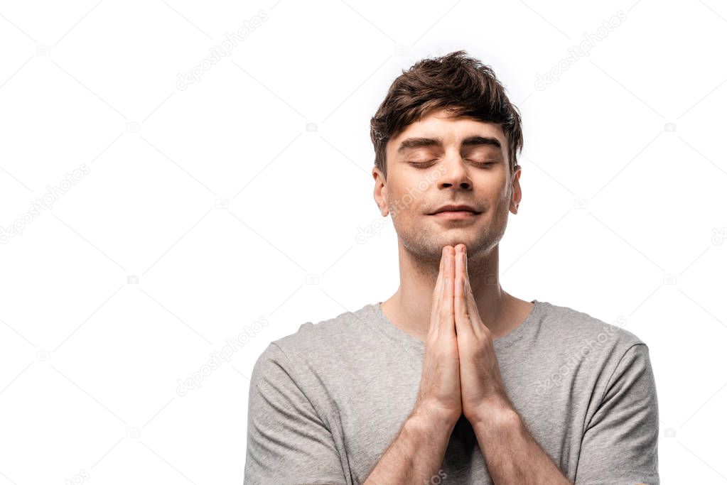 pensive man with closed eyes showing pray gesture and smiling isolated on white