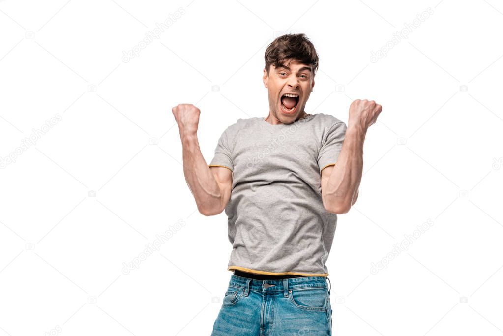 excited young man showing winner gesture while looking at camera isolated on white