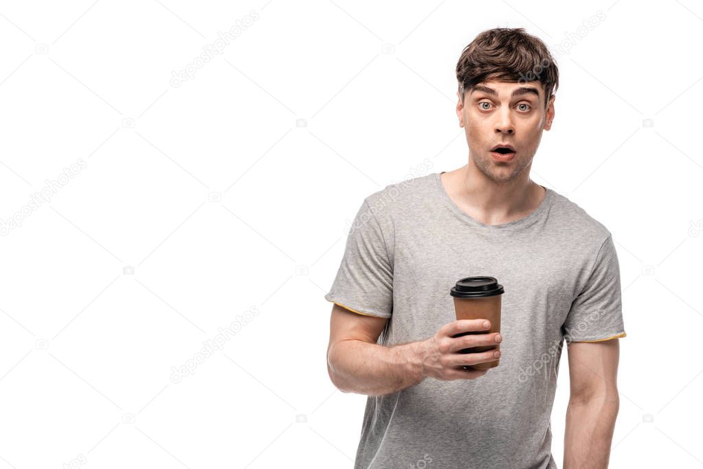 surprised young man looking at camera while holding coffee to go isolated on white