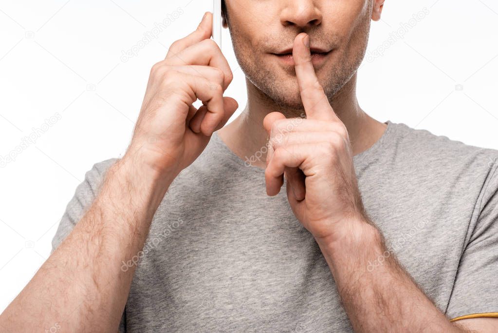 cropped view of man showing silence gesture while using smartphone isolated on white